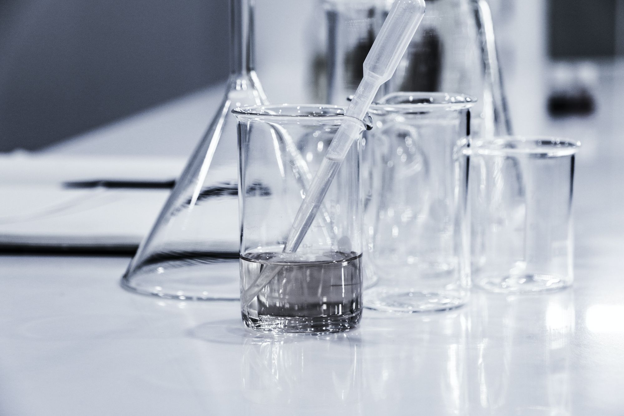 Several chemistry beakers and glassware with a pipette on a white lab table.