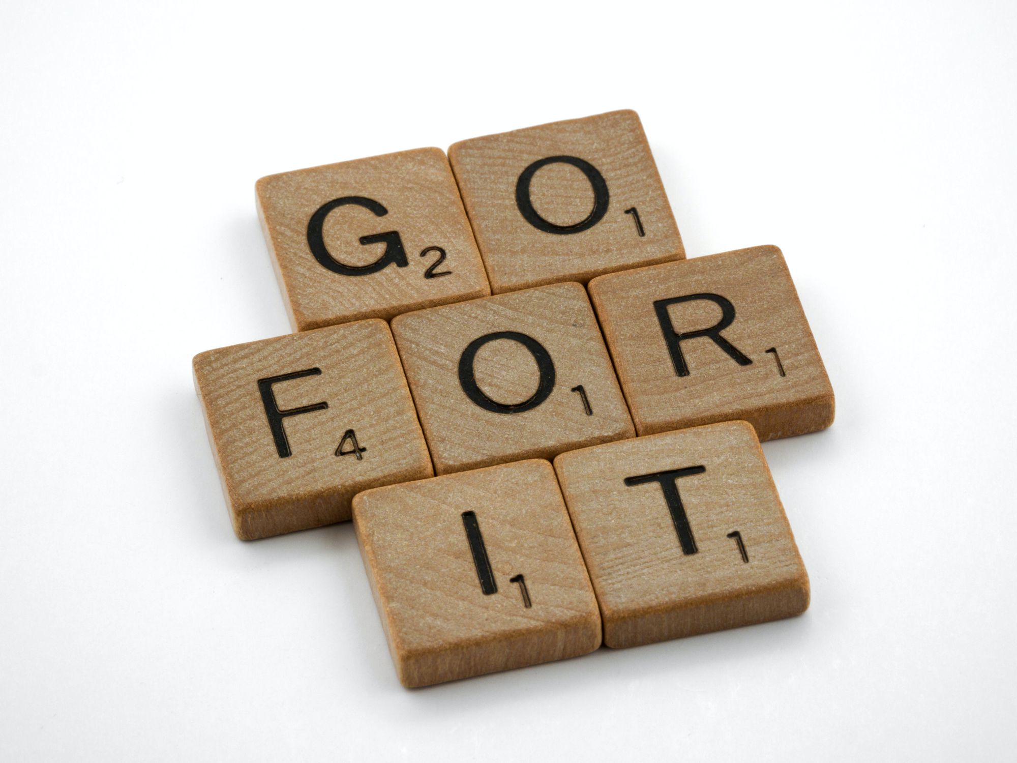 Wooden letters from the game of Scrabble spelling "go for it."