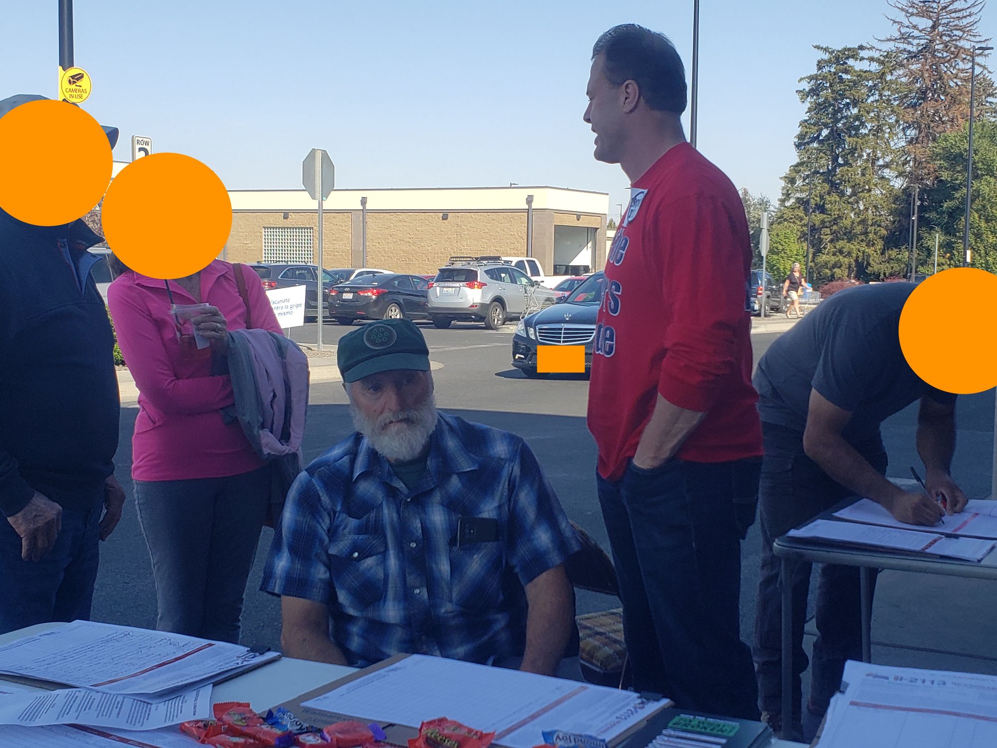Two men gather signatures for political initiatives in a Walmart parking lot.