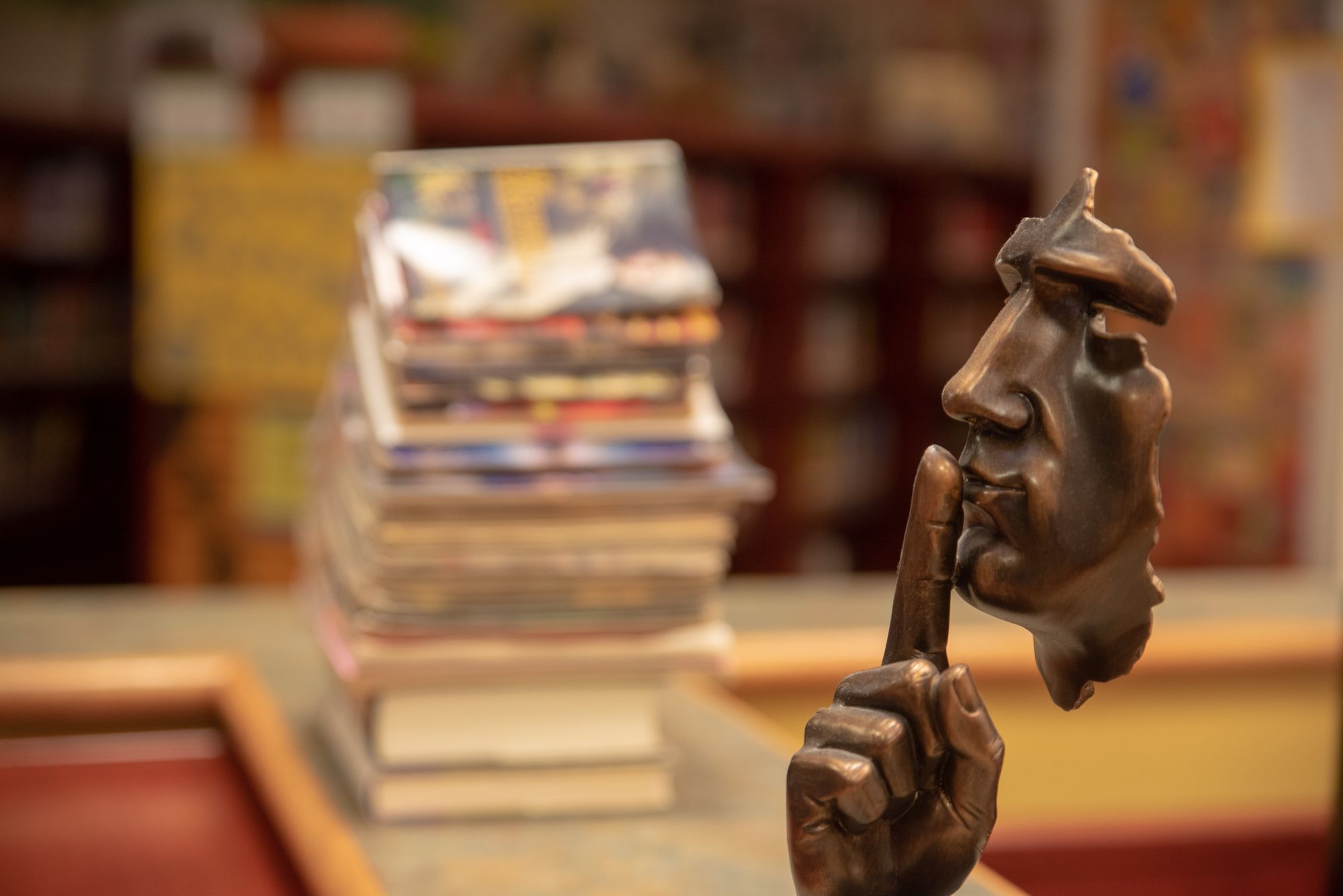 Bronze statue in a library holding a finger to lips for silence