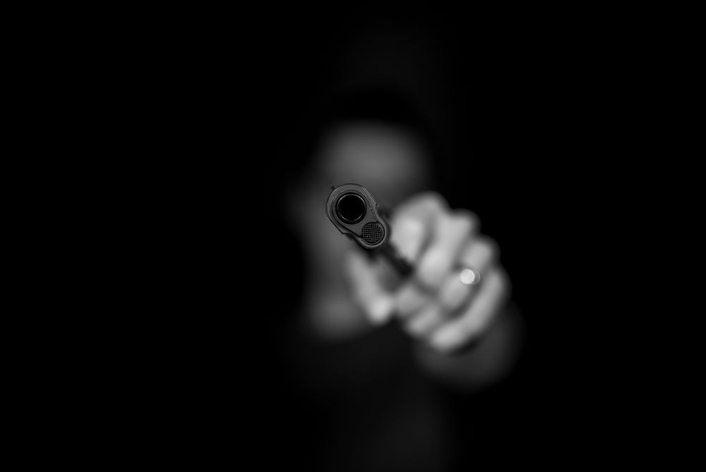 Black and white image of a person holding a handgun