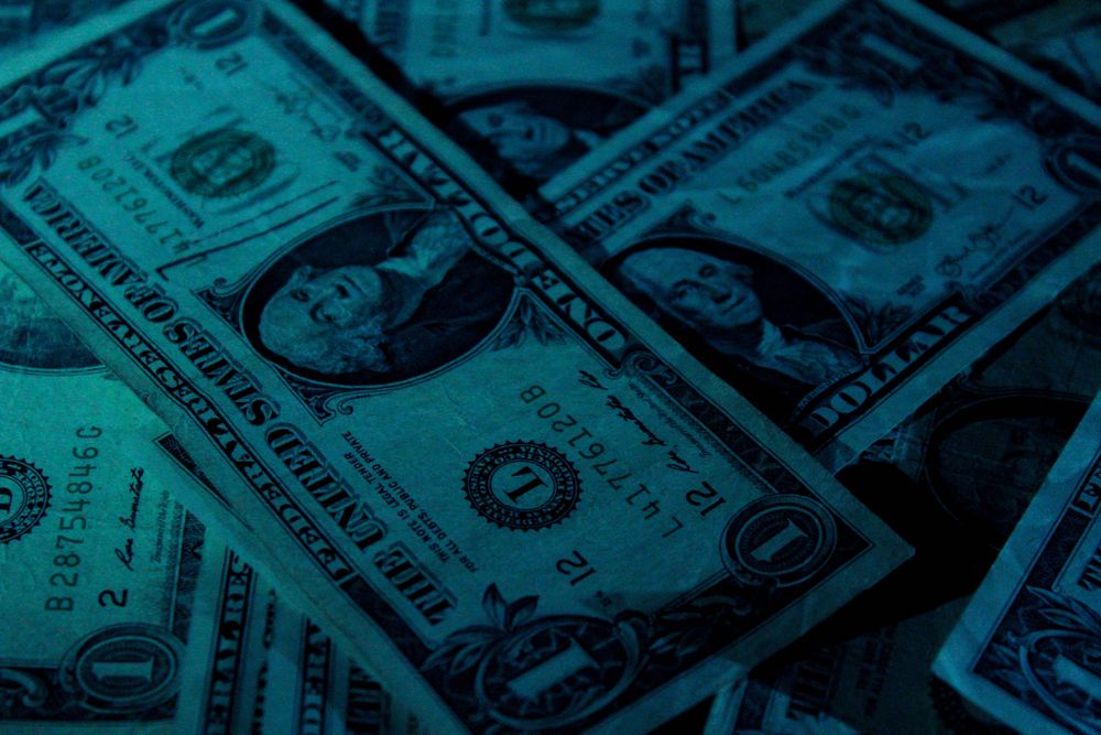One dollar bills in dark lighting.